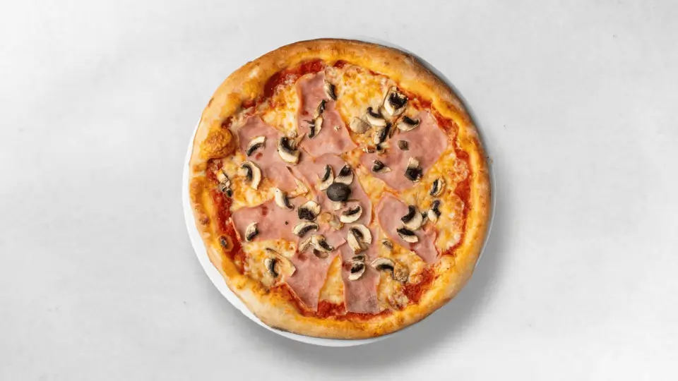 Pizza Capricciosa - Herzhafte Capricciosa-Pizza mit zartem Schinken und frischen Champignons, angerichtet auf einem goldbraunen Pizzateig.