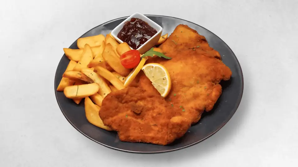 Klassisches Wiener Schnitzel, serviert mit Pommes oder Bratkartoffeln und Preiselbeeren für einen besonderen Geschmack